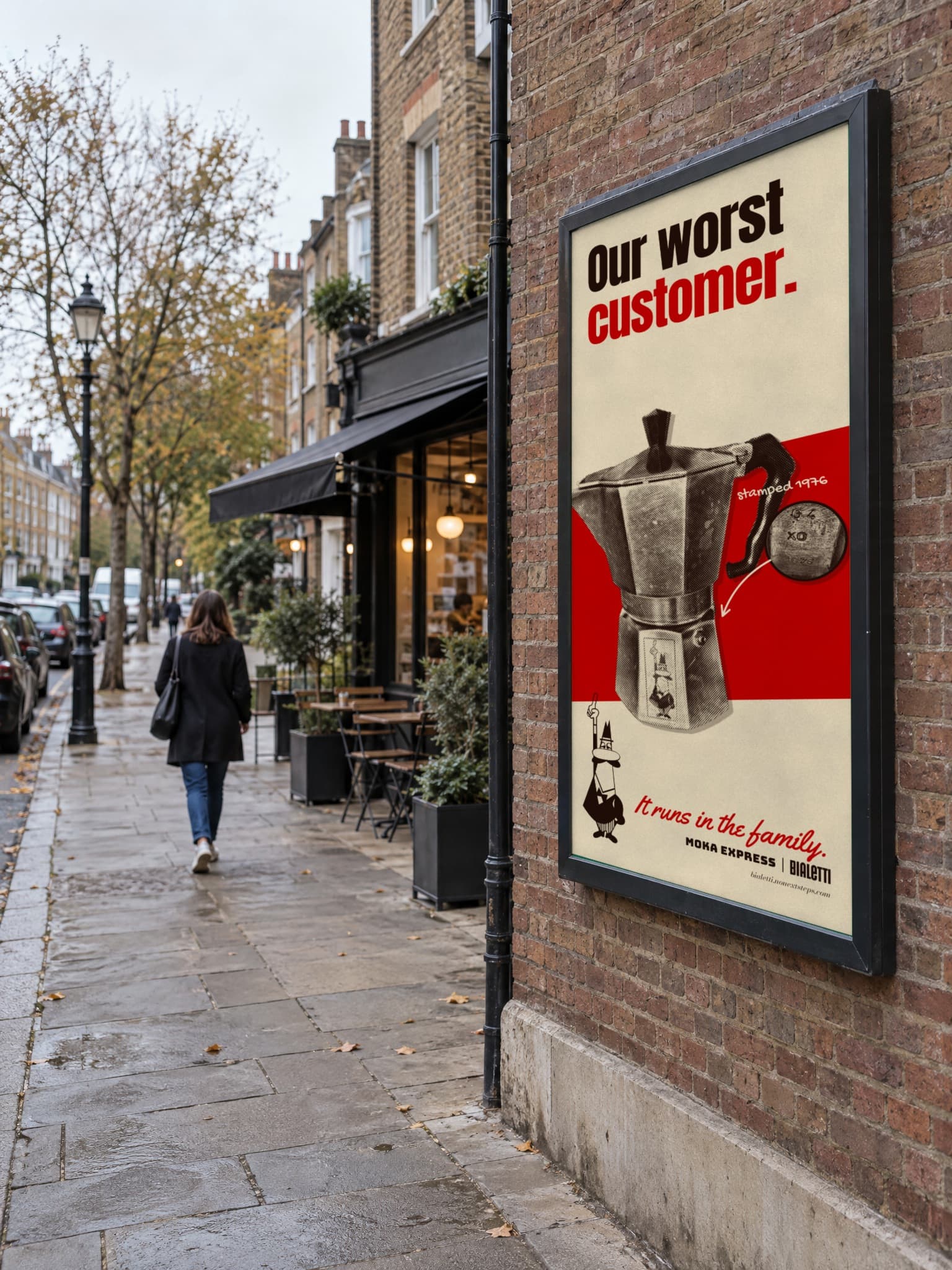 The Our worst customer. poster framed on a brick wall beside a café on a wet street, a woman walking past