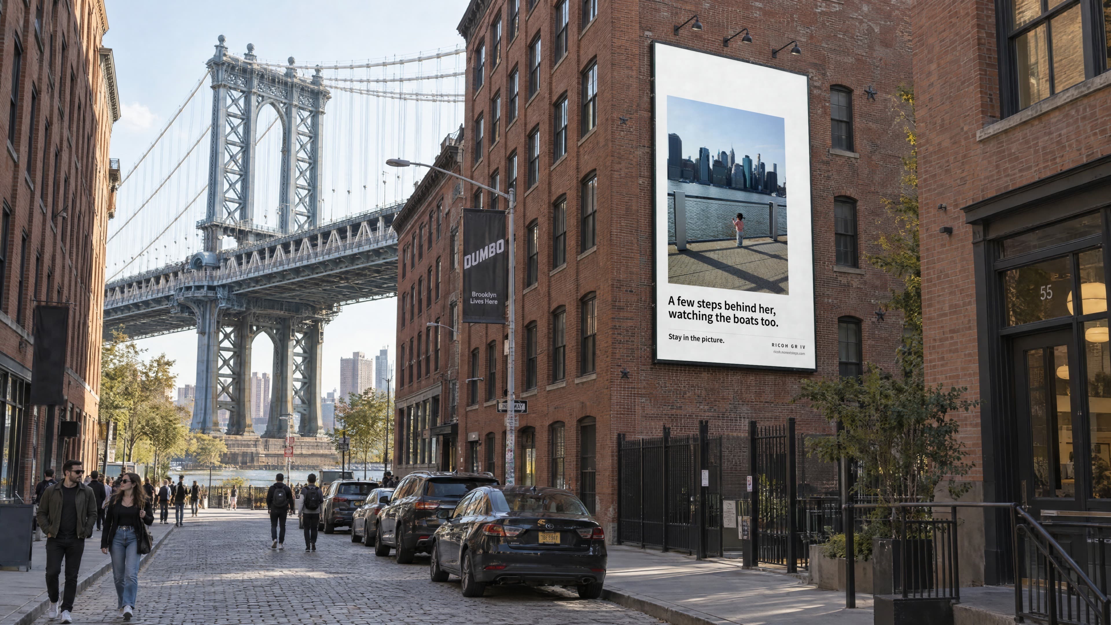 A wallscape on a brick warehouse in DUMBO, Brooklyn, near the Manhattan Bridge: a small girl at a railing watching the skyline, with the line A few steps behind her, watching the boats too.